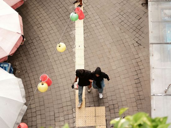 a couple of people walking down a street next to umbrellas