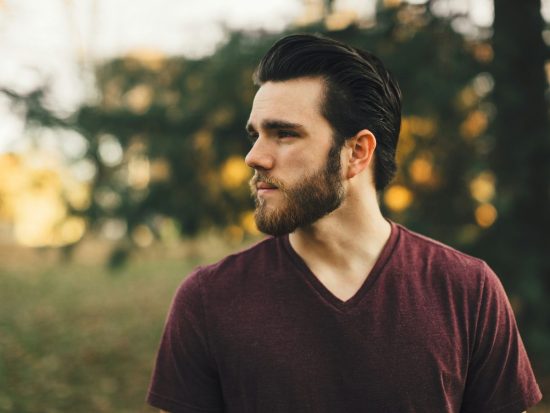 man wearing maroon V-neck t-shirt in forest