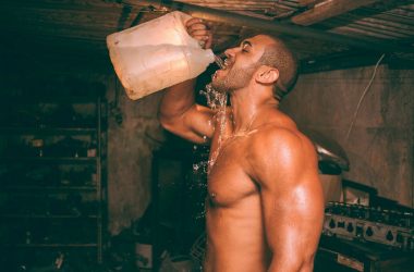 topless man drinking water from plastic container