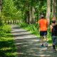 man in orange t-shirt and gray pants with blue shoes walking on pathway