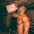 topless man drinking water from plastic container