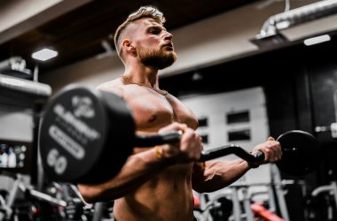 topless man in black shorts carrying black dumbbell