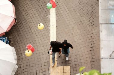 a couple of people walking down a street next to umbrellas