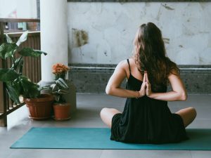 woman wearing black shirt sitting on green yoga mat