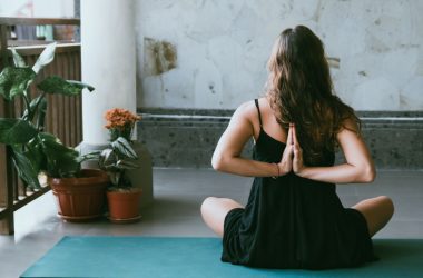 woman wearing black shirt sitting on green yoga mat