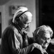 greyscale photo of woman standing behind woman sitting on chair