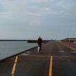 a man walking down a road next to a body of water