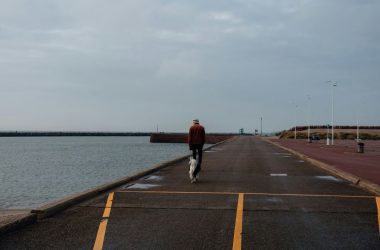 a man walking down a road next to a body of water